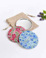 Blue Liberty fabric pocket mirror. Pretty blue floral Liberty of London fabric covers the back of the small round hand mirror.
The round pocket mirror measures 77mm in diameter and comes with a linen drawstring pouch.
Image shows the pretty pocket mirror sitting on top of the linen pouch.
Handmade by Stitch Galore.