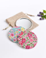 Pink Liberty fabric pocket mirror. Pretty pink floral Liberty of London fabric covers the back of the small round hand mirror.
The round pocket mirror measures 77mm in diameter and comes with a linen drawstring pouch.
Image shows the pretty pocket mirror sitting on top of the linen pouch.
Handmade by Stitch Galore.