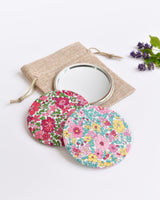 Floral Liberty fabric pocket mirror. Pretty floral Liberty of London fabric covers the back of the small round hand mirror.
The round pocket mirror measures 77mm in diameter and comes with a linen drawstring pouch.
Image shows the pretty pocket mirror sitting on top of the linen pouch.
Handmade by Stitch Galore.