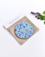 Blue Liberty fabric pocket mirror. Pretty blue floral Liberty of London fabric covers the back of the small round hand mirror.
The round pocket mirror measures 77mm in diameter and comes with a linen drawstring pouch.
Image shows the pretty pocket mirror sitting on top of the linen pouch.
Handmade by Stitch Galore.

