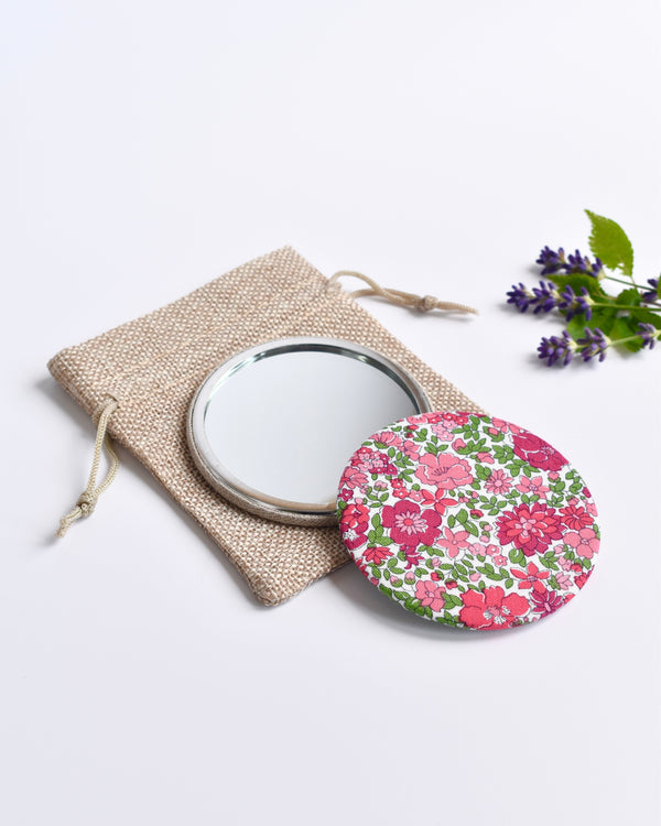Pink Liberty fabric pocket mirror. Pretty pink floral Liberty of London fabric covers the back of the small round hand mirror.
The round pocket mirror measures 77mm in diameter and comes with a linen drawstring pouch.
Image shows the pretty pocket mirror sitting on top of the linen pouch.
Handmade by Stitch Galore.

