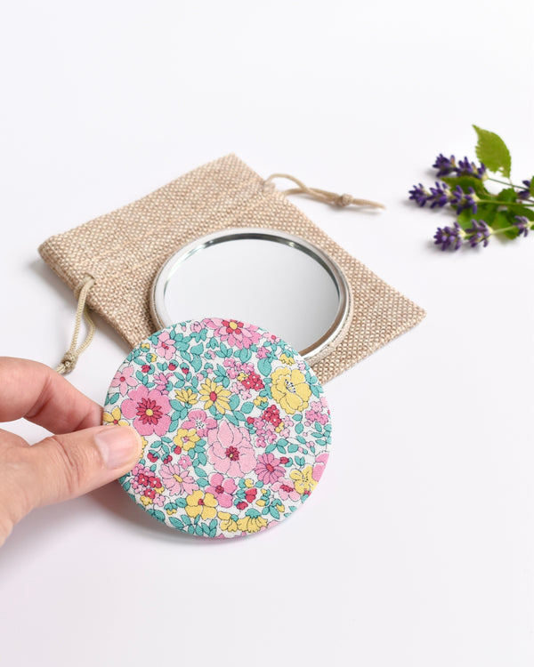 Floral Liberty fabric pocket mirror. Pretty floral Liberty of London fabric covers the back of the small round hand mirror.
The round pocket mirror measures 77mm in diameter and comes with a linen drawstring pouch.
Image shows the pretty pocket mirror sitting on top of the linen pouch.
Handmade by Stitch Galore.
